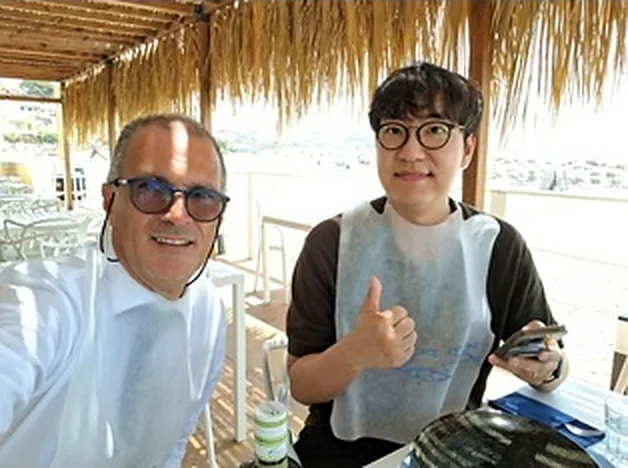 Due ospiti a tavola, sotto un pergolato sul mare