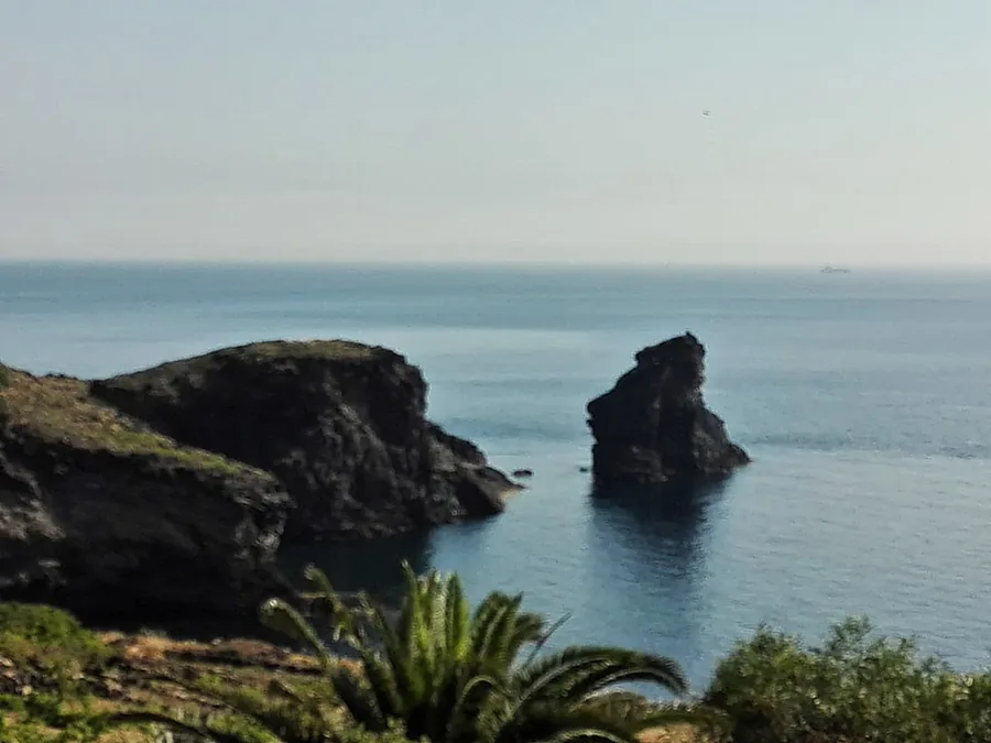 La costa de roca oscura y un farallón en el mar