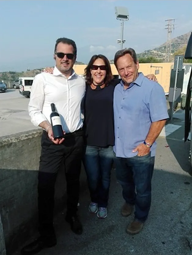Tre persone all'aperto, una di loro con una bottiglia di vino