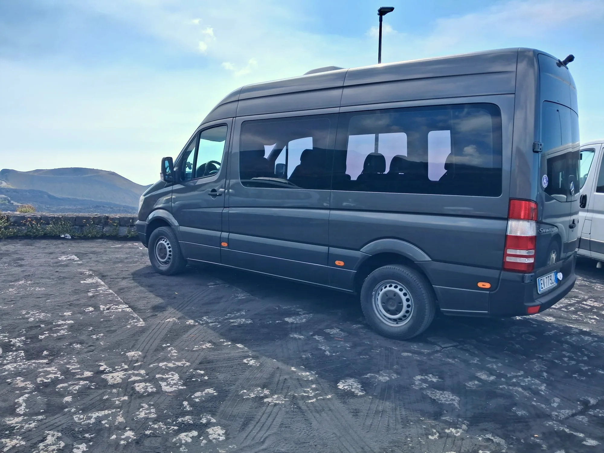 Il Mercedes-Benz Sprinter grigio scuro di Exclusive Journeys di tre quarti sulla sabbia vulcanica dell'Etna