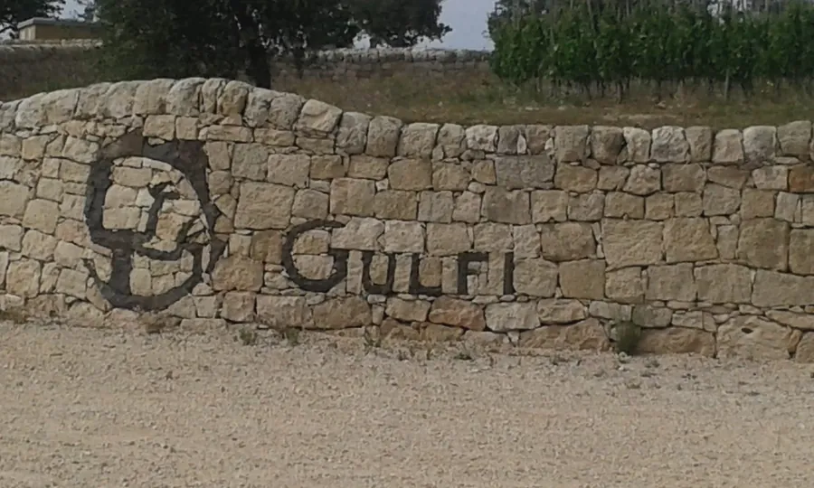 Il muro a secco con la scritta Gulfi all'ingresso della tenuta, fra i vigneti