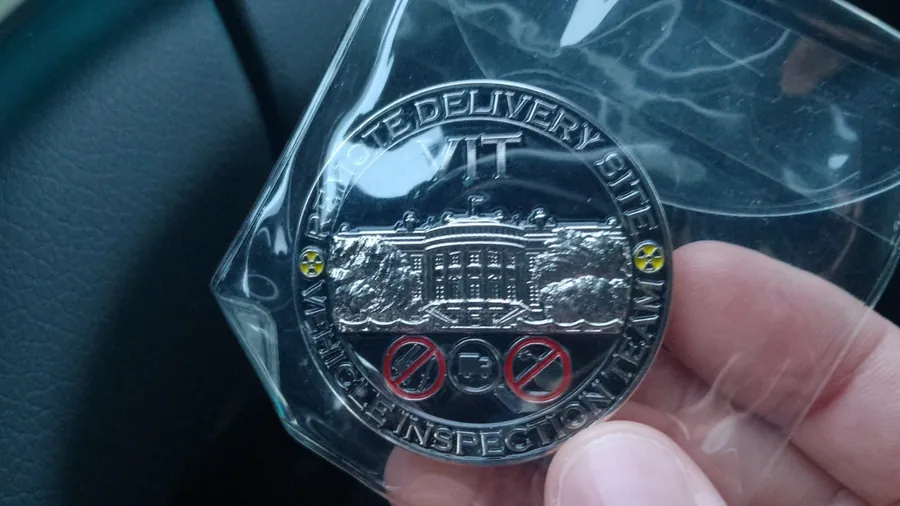 Una moneta d'argento del Vehicle Inspection Team, tenuta in mano