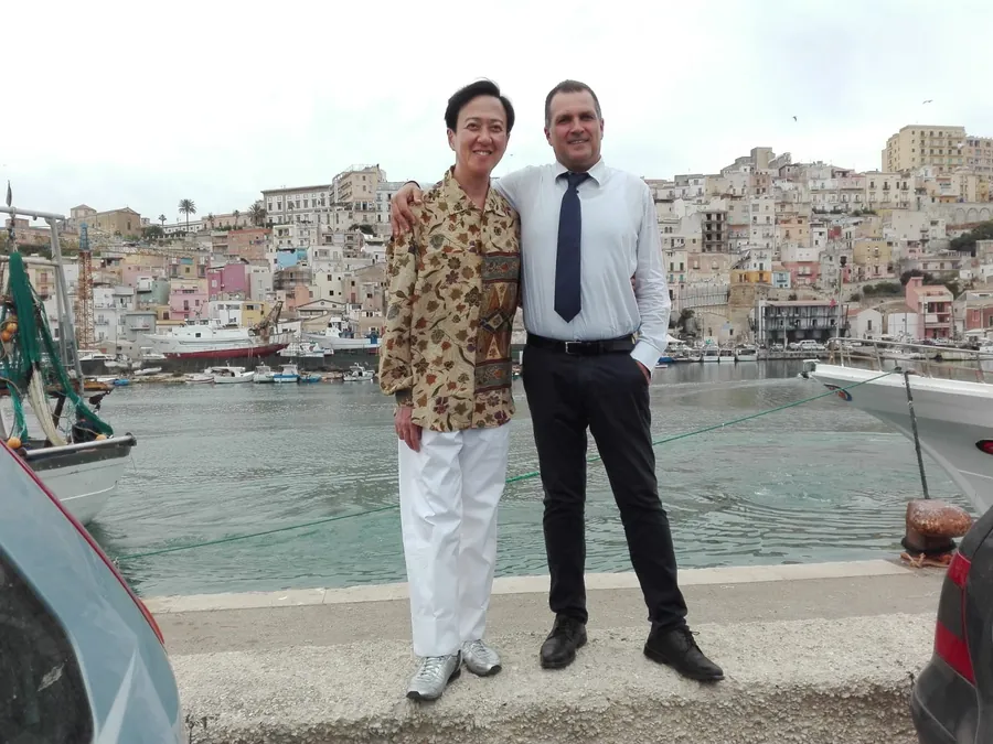 L'autista e un'ospite sulla banchina di un porto, con le case colorate alle spalle