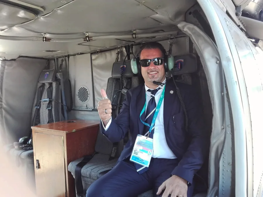 Un chófer con traje oscuro y auriculares, a bordo de un helicóptero, con el pulgar hacia arriba