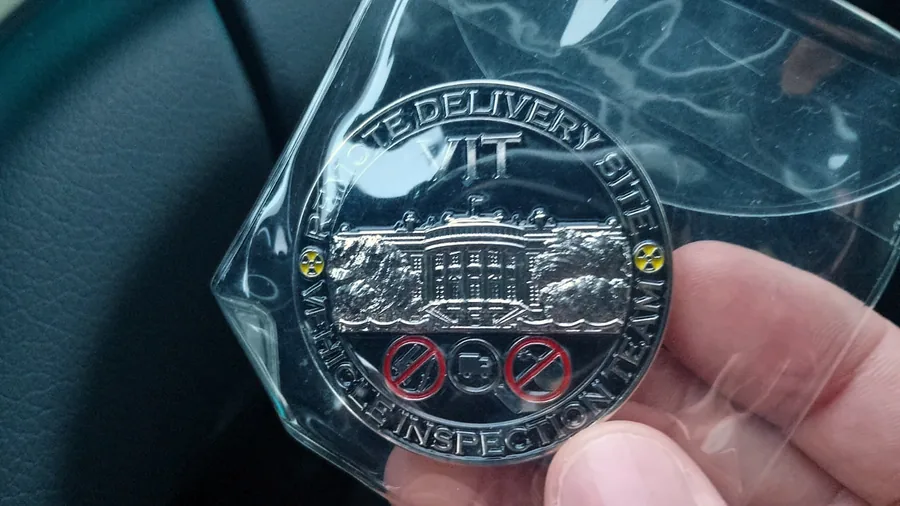 Una moneda de plata del Vehicle Inspection Team, sostenida en la mano