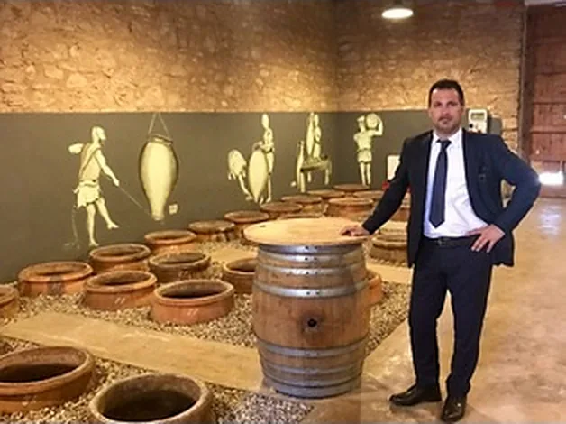 Una cantina con le anfore di terracotta interrate e una botte di legno in primo piano