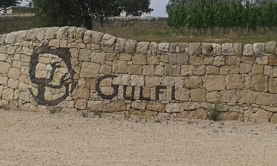 Die Trockenmauer mit dem Schriftzug Gulfi am Eingang des Weinguts, zwischen den Weinbergen