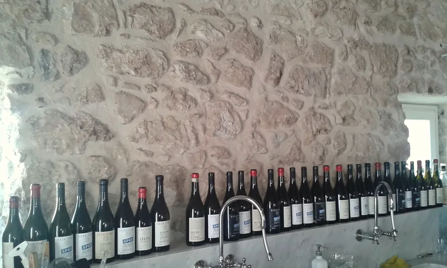 Eine Reihe Weinflaschen auf einem Marmorbord vor einer Steinmauer