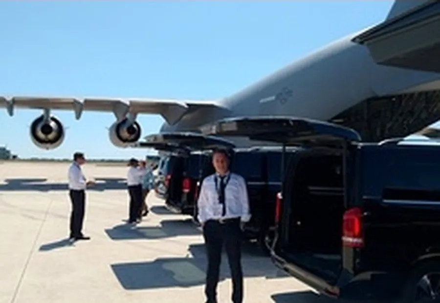 Auto di servizio sotto l'ala di un aereo, su una pista