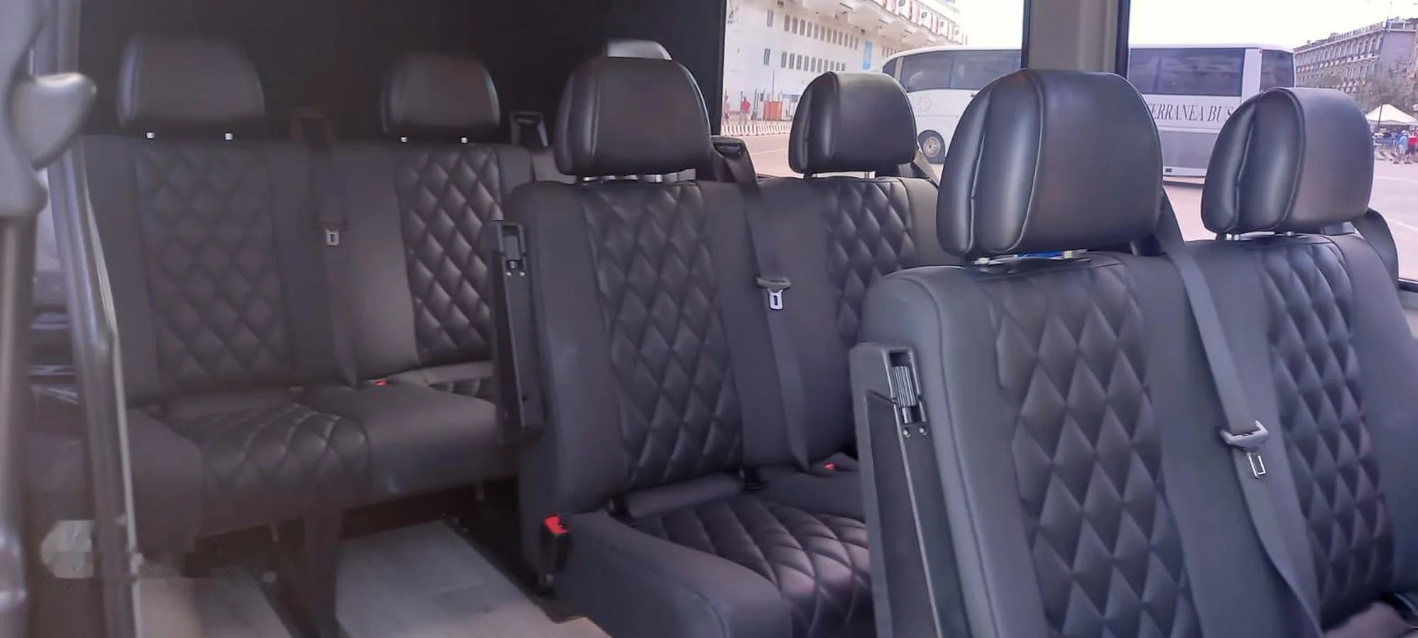 Le file di sedili in pelle trapuntata viste dalla porta laterale aperta