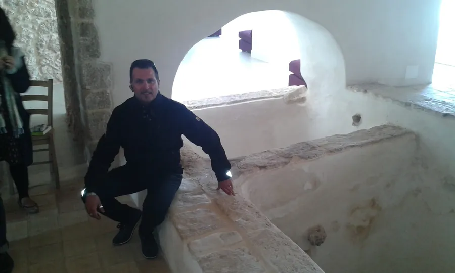 La visita in cantina, fra le vasche in pietra sotto un arco bianco
