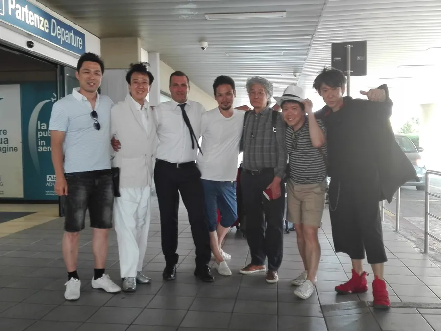 Un gruppo davanti all'ingresso delle partenze di un aeroporto, a fine viaggio